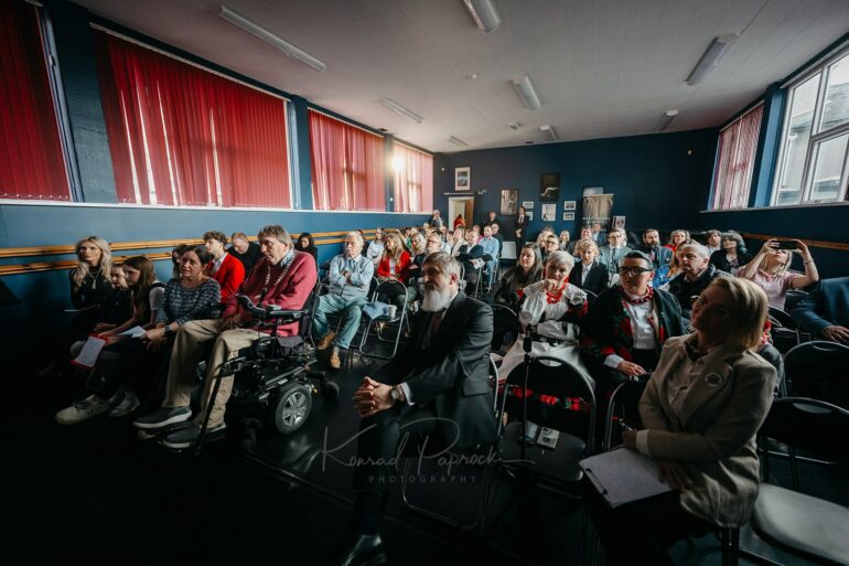 Cztery święta, jeden wieczór
Uroczystość rozpoczęła się o godz. 19:00. Sala była wypełniona Polakami i Irlandczykami, od małych dzieci po dorosłych. Po kolei odśpiewano hymny narodowe Polski i Irlandii. Ten ostatni zaśpiewał John O’Carroll – chórzysta i mąż Polki, który od ponad pięćdziesięciu lat ma więzi z Polską. Jego głęboki bas wypełnił salę i – jak przyznał Major Tralee – „prawie zrzucił mnie z wózka”.
Ambasador Artur Michalski przypomniał zgromadzonym, że Konstytucja 3 maja obchodzi w tym roku 235. rocznicę. Jest to najstarsza konstytucja w Europie – przyjęta cztery miesiące przed konstytucją francuską – i choć nigdy nie weszła w życie, od wieków stanowi dla Polaków symbol wolności i nowoczesnego myślenia. „Pomimo rozbiorów i 123 lat obcej władzy ta konstytucja zawsze wskazywała nam drogę” – podkreślił ambasador.